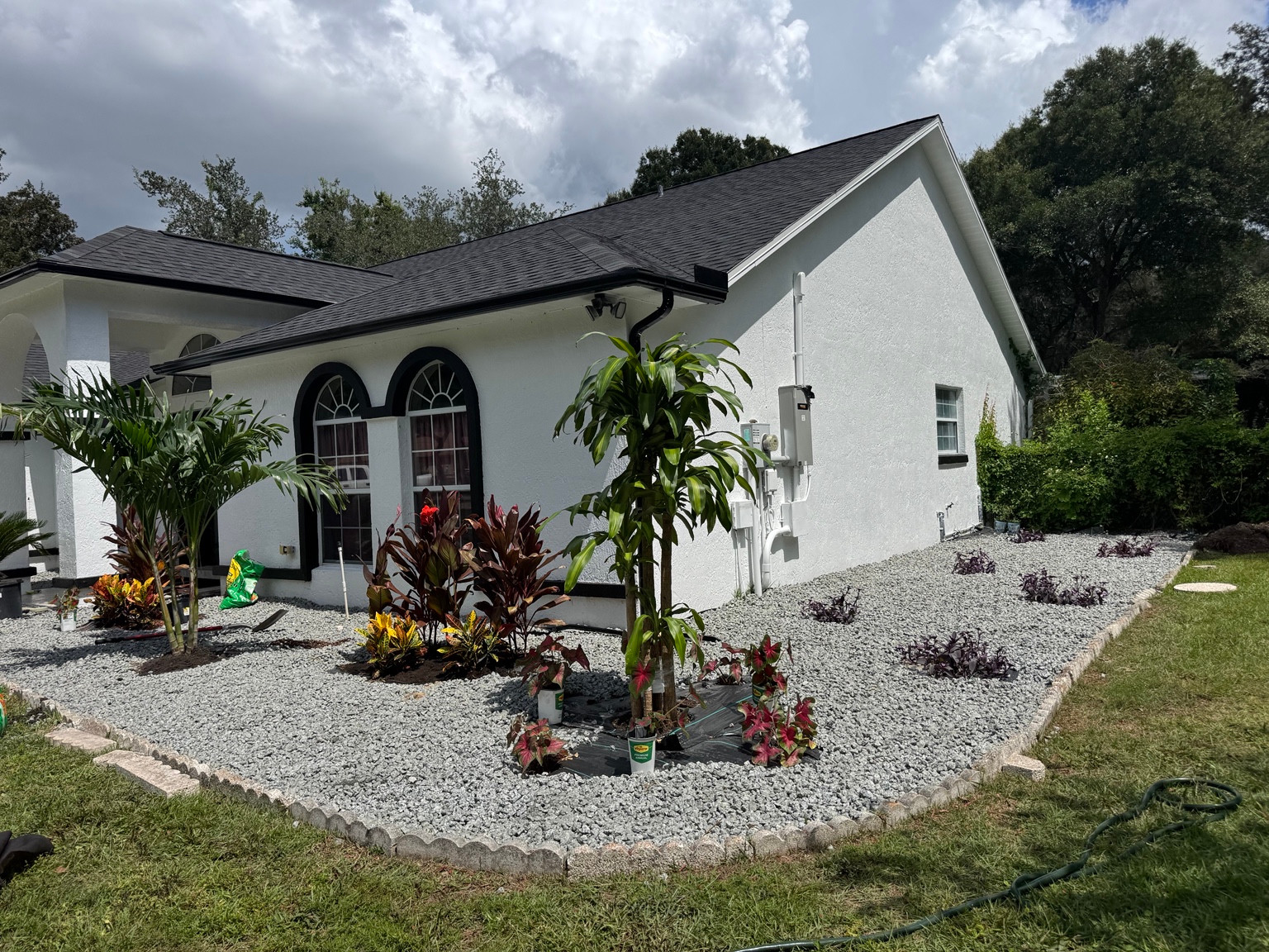 Landscaping project with decorative stone, border edging, and tropical plants beside a Florida home